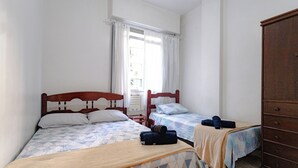 A bedroom with two beds, a wooden wardrobe, and a window with curtains. - 360 Copa Beach NSC By SUHCasa (Rio de Janeiro)