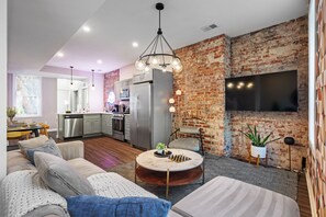 A modern living room with a sofa, coffee table, and a brick wall. - Modern 3BR, 2BA Home: 2 King Beds, Off Street Parking; Near Downtown Pittsburgh  (Pittsburgh)