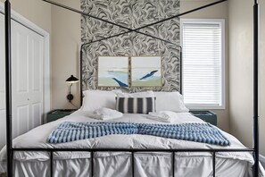 Relax in a stylish bedroom with a four-poster bed, adorned with a striped blanket and framed artworks.
