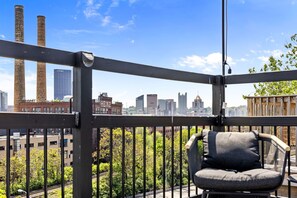 Enjoy breathtaking views of the city skyline from this balcony with a single comfortable chair.