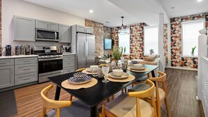 A modern kitchen with grey cabinets, a black countertop, and a dining area with a black table and wooden chairs.