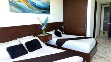 Habitación de hotel con dos camas, cabecero de madera, mesita de noche con un florero y un cuadro abstracto grande en la pared.