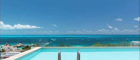 Una piscina al aire libre, sillones reclinables de piscina