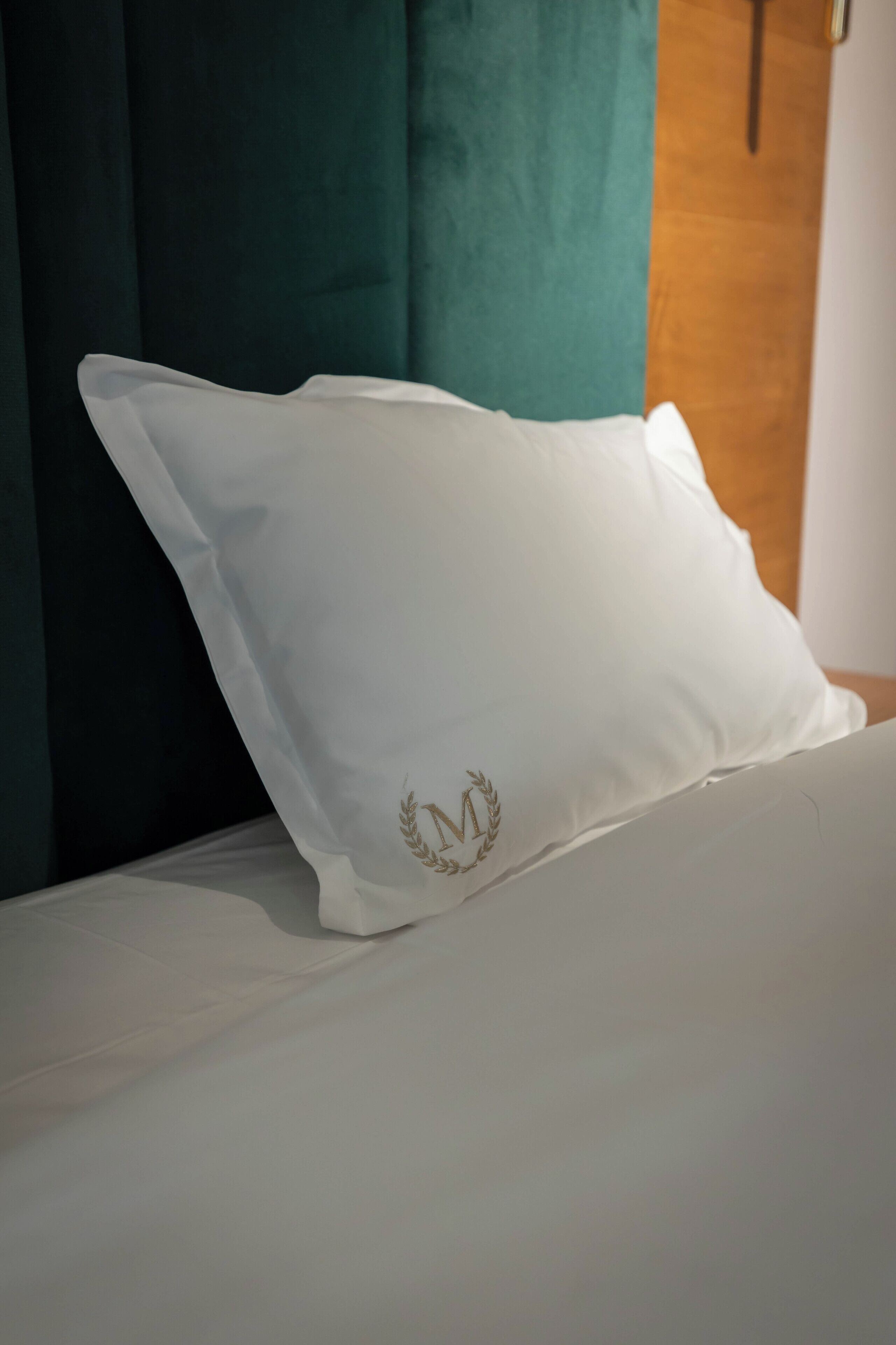 Un cuscino bianco con uno stemma dorato su un letto.