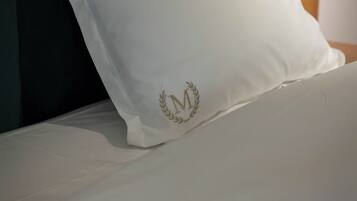 Un cuscino bianco con uno stemma dorato su un letto.