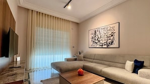 Una sala moderna con un sofá grande, una mesa de centro y un televisor de pantalla plana.