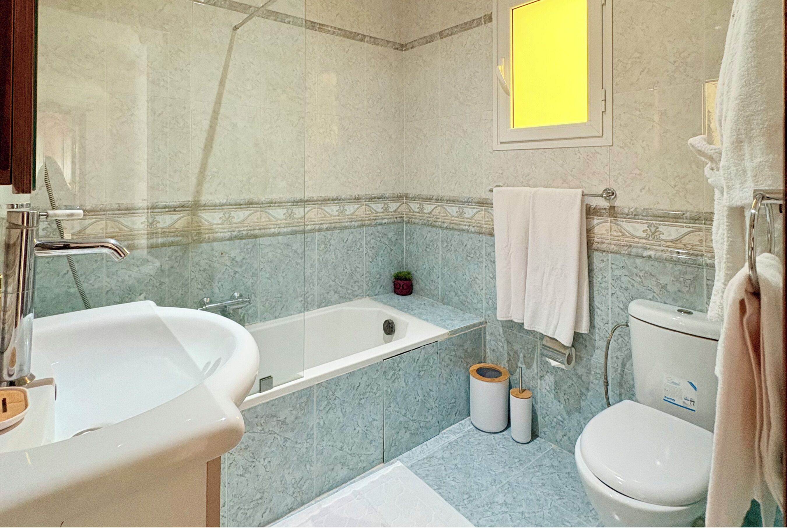 Un baño con bañera, lavabo, inodoro y una pequeña planta en maceta.
