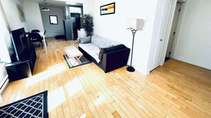 A modern living room with a sofa, a TV, a lamp, and a wooden floor.