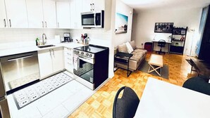Ein kompakter Wohnbereich mit Küchenzeile, Essbereich und einer Sitzecke mit Sofa und kleinem Tisch.