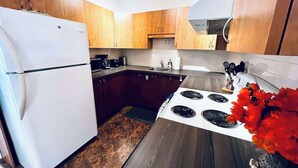Una cocina moderna con armarios de madera, un refrigerador blanco, una estufa y un lavamanos.