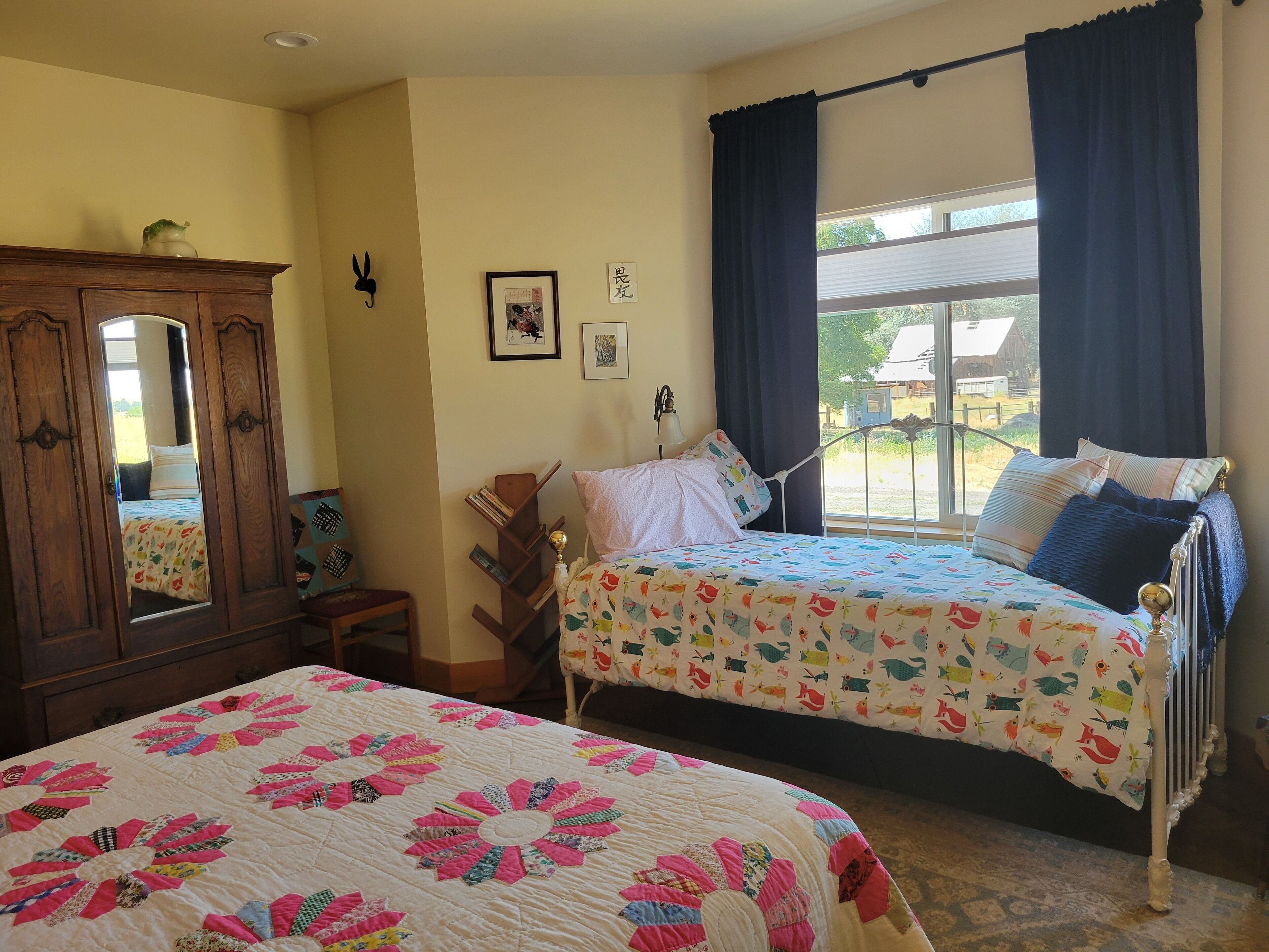 Un dormitorio con dos camas, un armario de madera, un espejo y una ventana con cortinas.