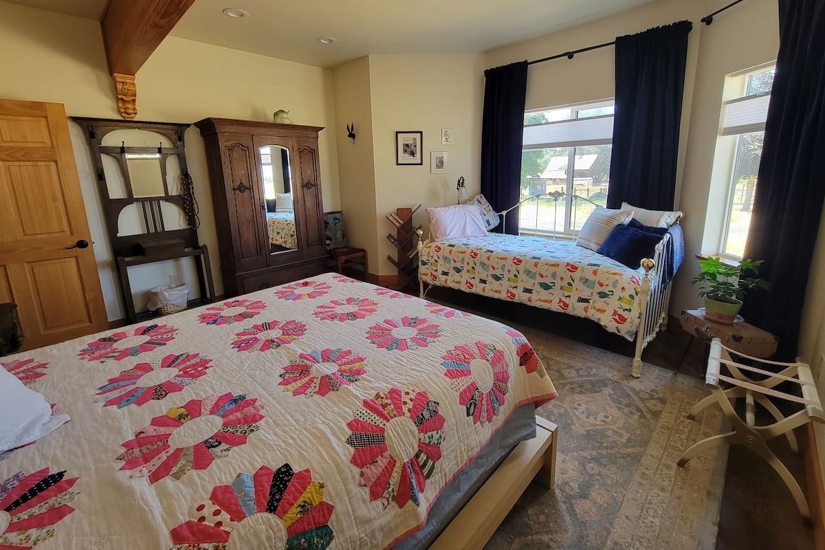 Un dormitorio con dos camas, un armario de madera, un espejo y una ventana con cortinas.