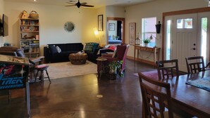 A spacious living room with a dark-colored sofa, a wooden coffee table, and a dining area with a wooden table and chairs. - 8 Mile Farm B&B (The Dalles)