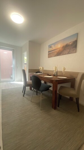 A dining area with a wooden table, four chairs, and a painting on the wall. - 2.5-room apartment with a washing machine and a kitchen in Freiburg (Freiburg im Breisgau)