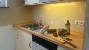 Et moderne køkken med lyse træskabe, en stålvask og en opvaskemaskine.