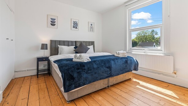 A bedroom with a bed, a nightstand, a window with a view, and wall art.