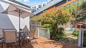 An outdoor patio with a table and chairs, a large umbrella, and a wooden deck.