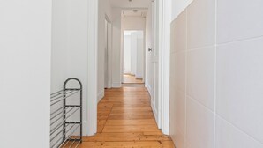 A narrow hallway with wooden flooring and white walls.