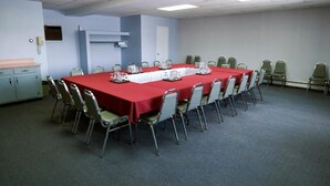 Una sala conferenze con un lungo tavolo, sedie e angolo cottura.
