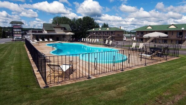 Un motel con piscina, area salotto esterna e un cartello.