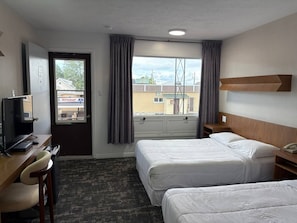 A hotel room with two beds, a desk with a chair, a television, and a window with curtains. - Daigle Motel (Saint-Léonard)