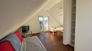 A room with a bed, a TV on a glass table, a wooden desk, and a sliding door to a balcony. - Modern 5-bedroom house on the Tuniberg in Fribourg (Freiburg im Breisgau)