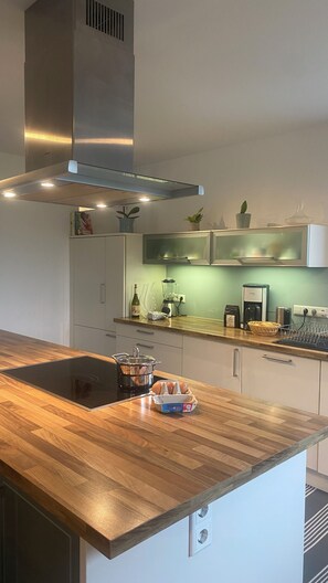 A modern kitchen with a wooden countertop, stainless steel appliances, and a built-in oven. - Modern 5-bedroom house on the Tuniberg in Fribourg (Freiburg im Breisgau)