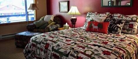 Un dormitorio con una cama grande, una ventana con persianas, una lámpara de noche y un espejo en la pared.