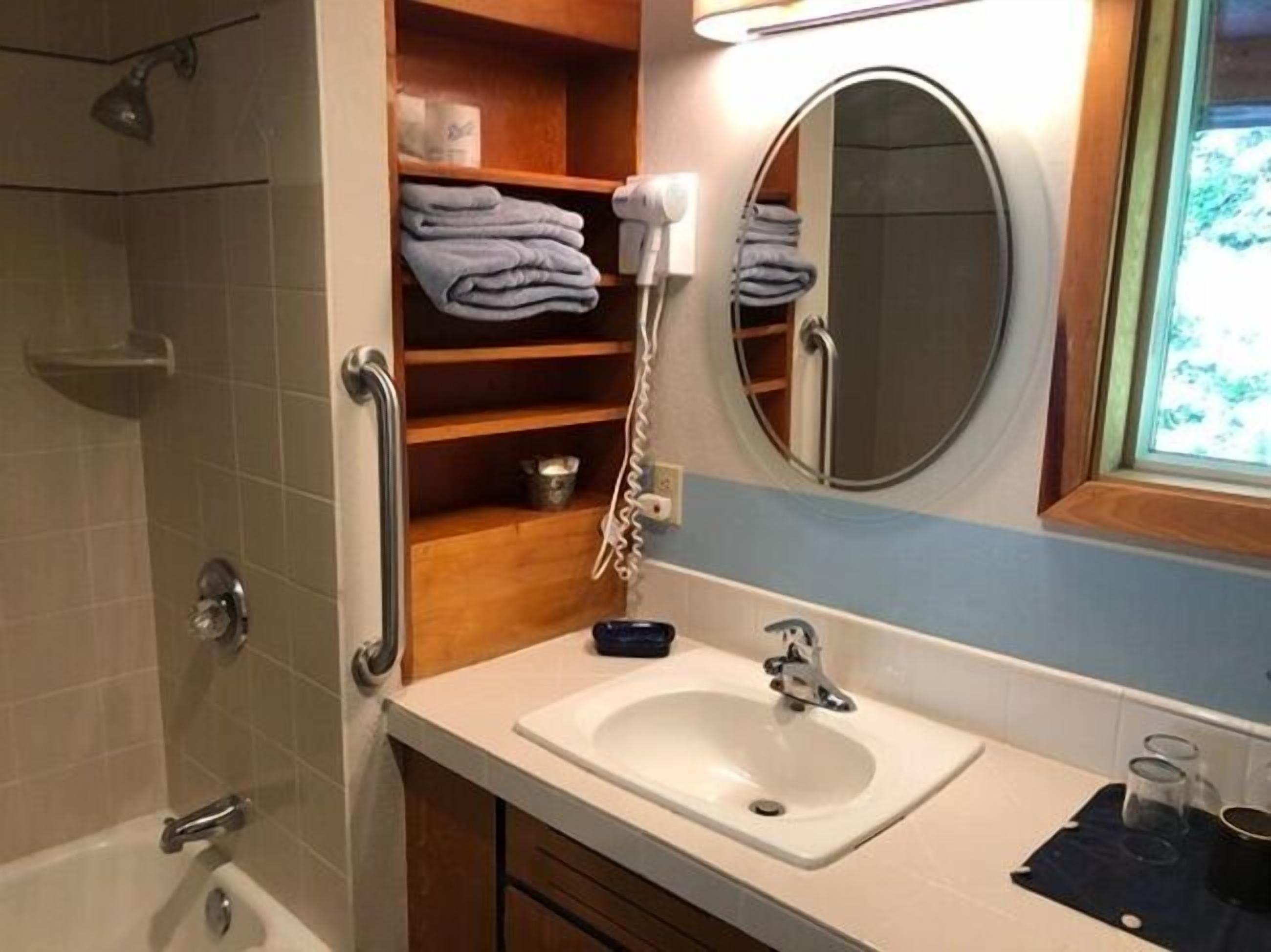 Een badkamer met een wit wastafel, een spiegel, een handdoekhouder en een douche.