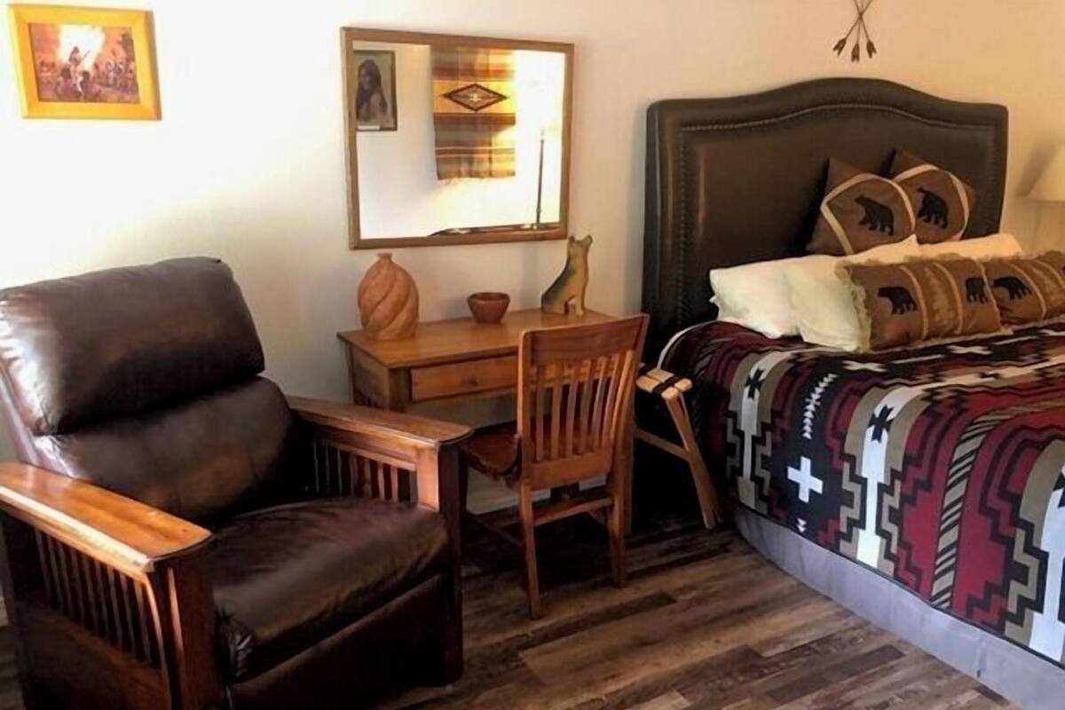 Un dormitorio con cama, escritorio, silla y espejo.