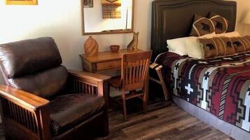 Un dormitorio con cama, escritorio, silla y espejo.