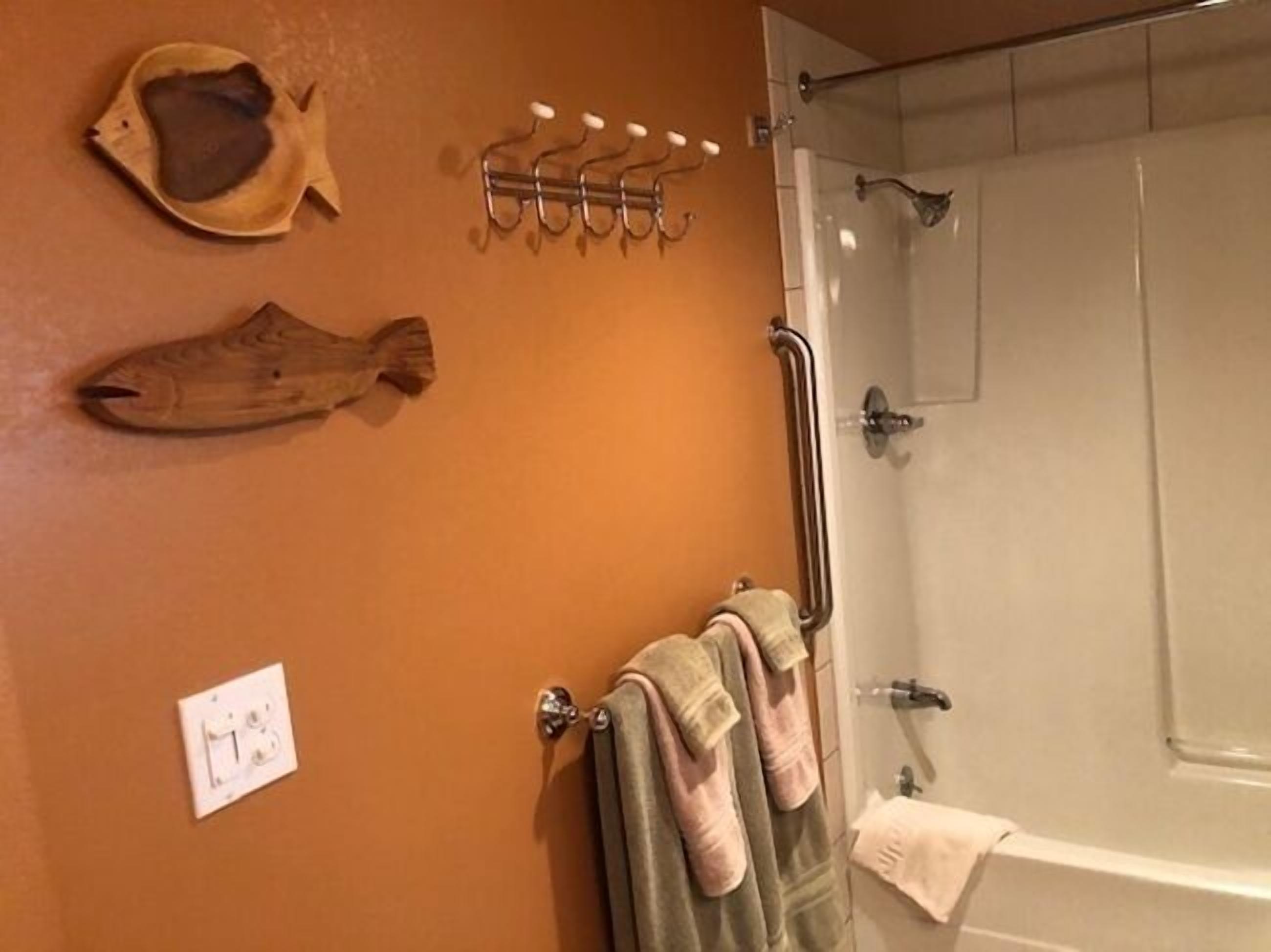 A bathroom with a wooden fish decoration, a towel rack, and a shower.