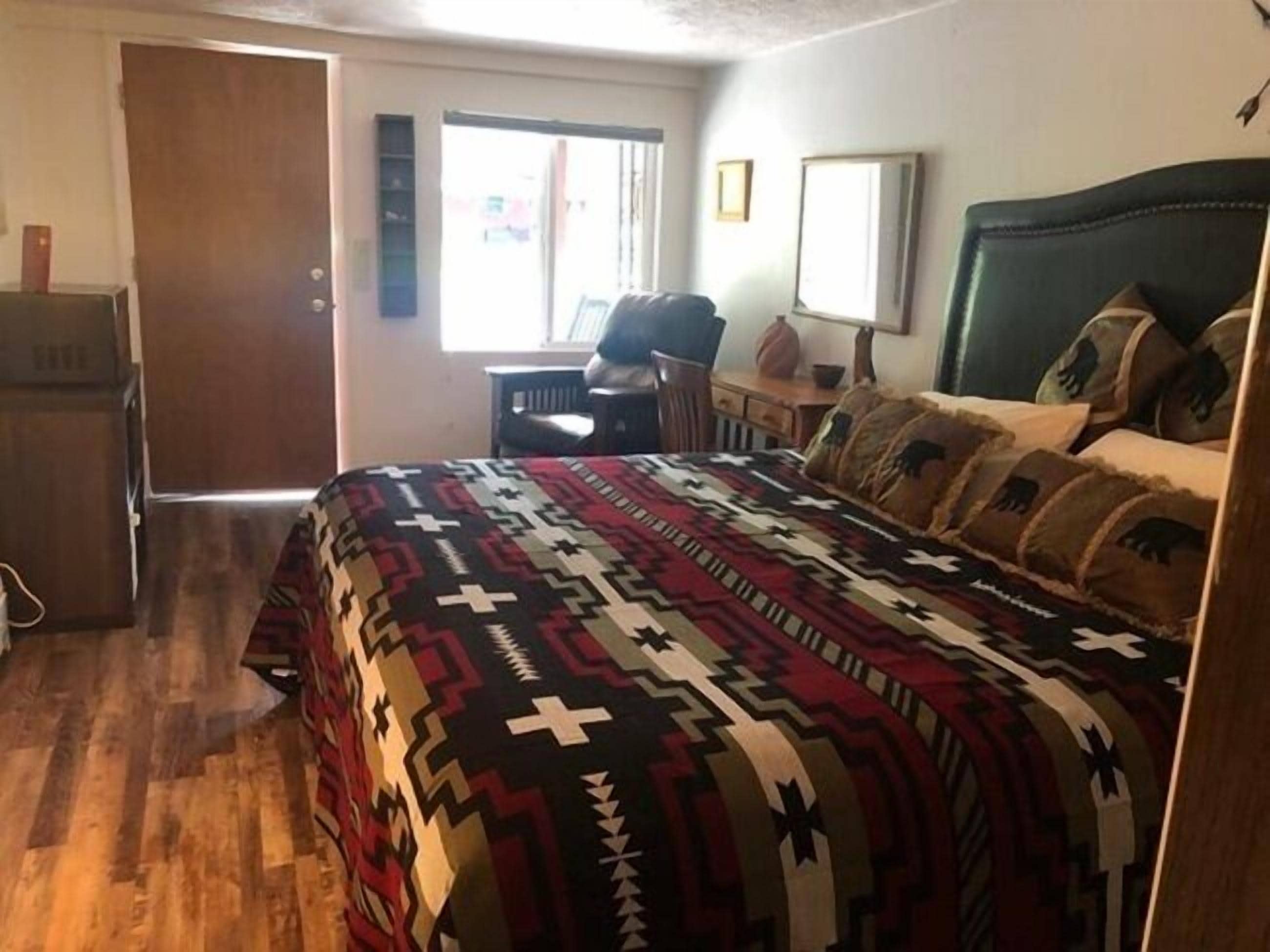 Un dormitorio con una cama grande, un escritorio, una silla y un refrigerador.