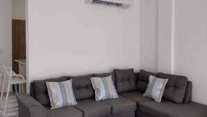 A modern living room with a grey sectional sofa, two matching ottomans, and patterned throw pillows. - Charming 2-bedroom apartment with WiFi, AC in enchanting Las Terrenas (Las Terrenas)