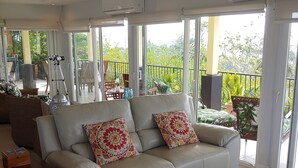 A spacious living room with a beige sofa set, a coffee table with fruit, and a balcony with potted plants. - Playa Hermosa Ocean View Estate (Playa Hermosa)