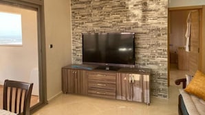 A modern living room with a stone-patterned wall, a flat-screen TV, and a wooden cabinet.