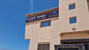 A building with a sign reading "La Perle De L'Océan" indicating a luxury apartment for rent.