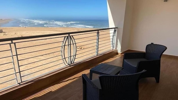 A balcony with a view of the beach and ocean.