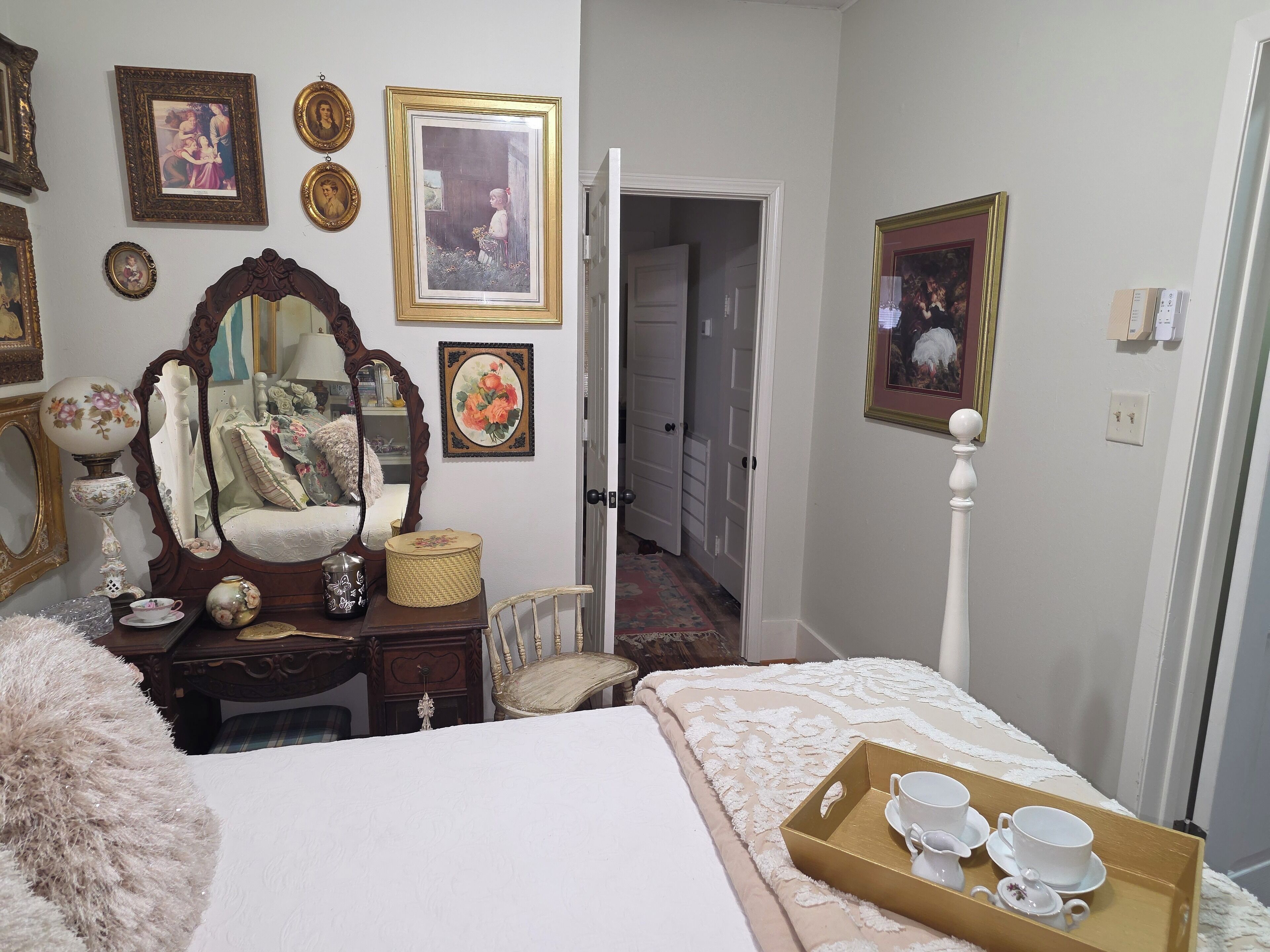 A bedroom with a bed, a dresser, a mirror, and a tray with cups and saucers.