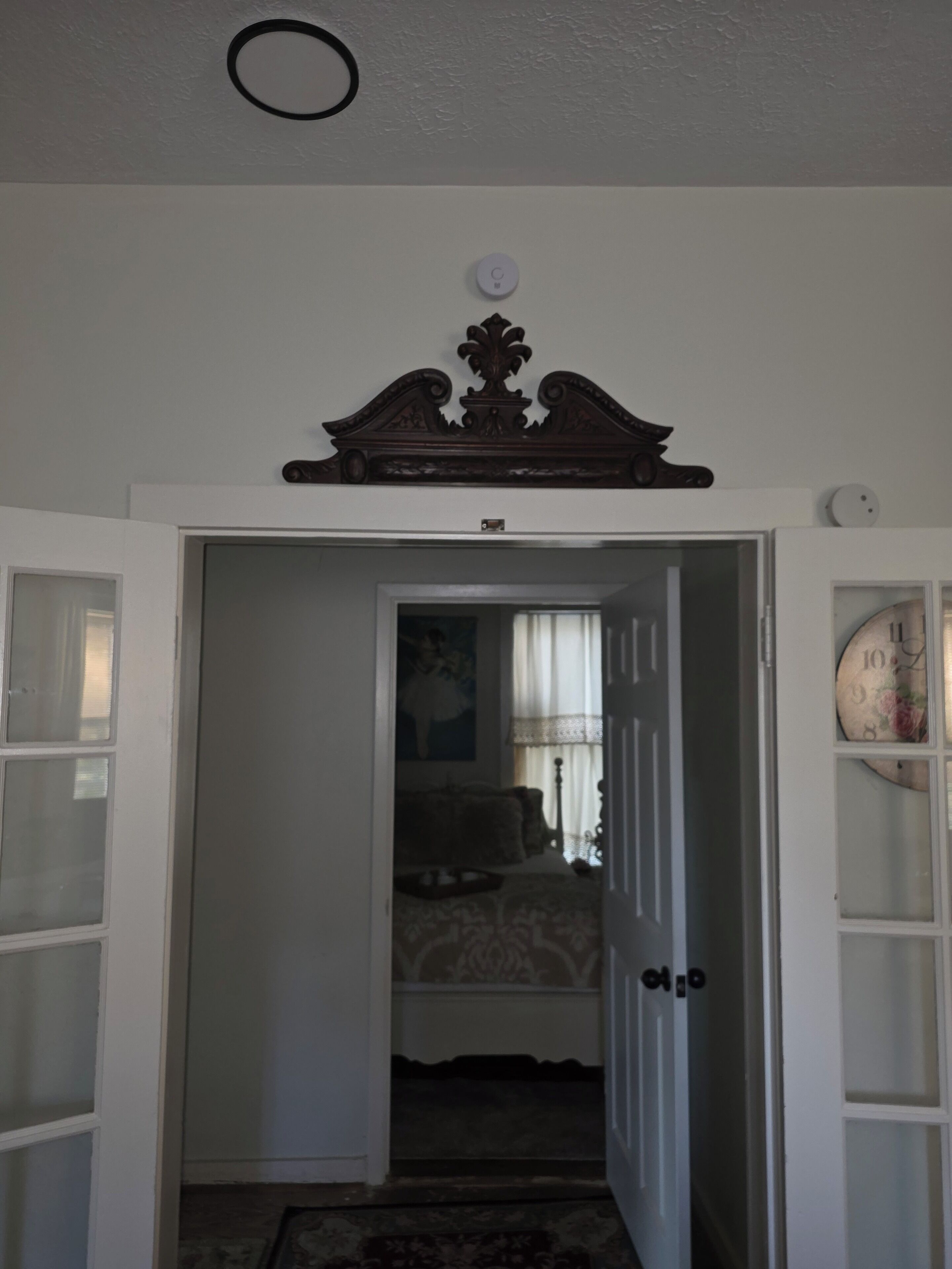 Corredor que dá para um quarto com uma cama, mesa de cabeceira e cômoda.