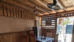Een houten eethoek met een tafel, stoelen, een koelkast en een plafondventilator.