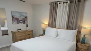 Una camera da letto con un letto grande, due comodini con lampade, una cassettiera in legno, un quadro appeso alla parete e una luce a soffitto.
