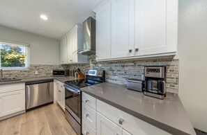 Enjoy cooking in this well-lit kitchen with a stainless steel dishwasher, oven, and coffee maker.