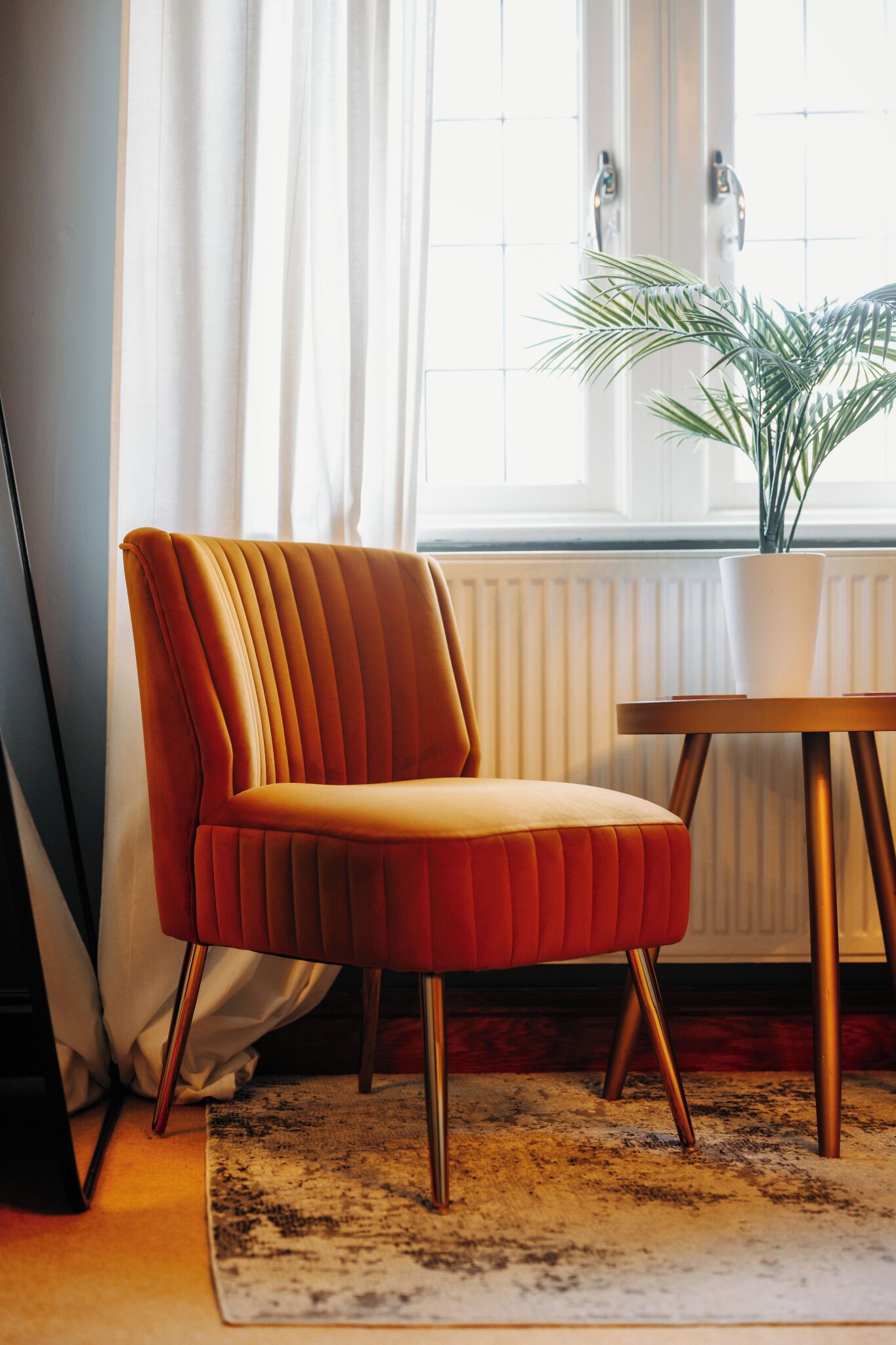 A modern room with a red upholstered chair, a wooden table, and a potted plant.