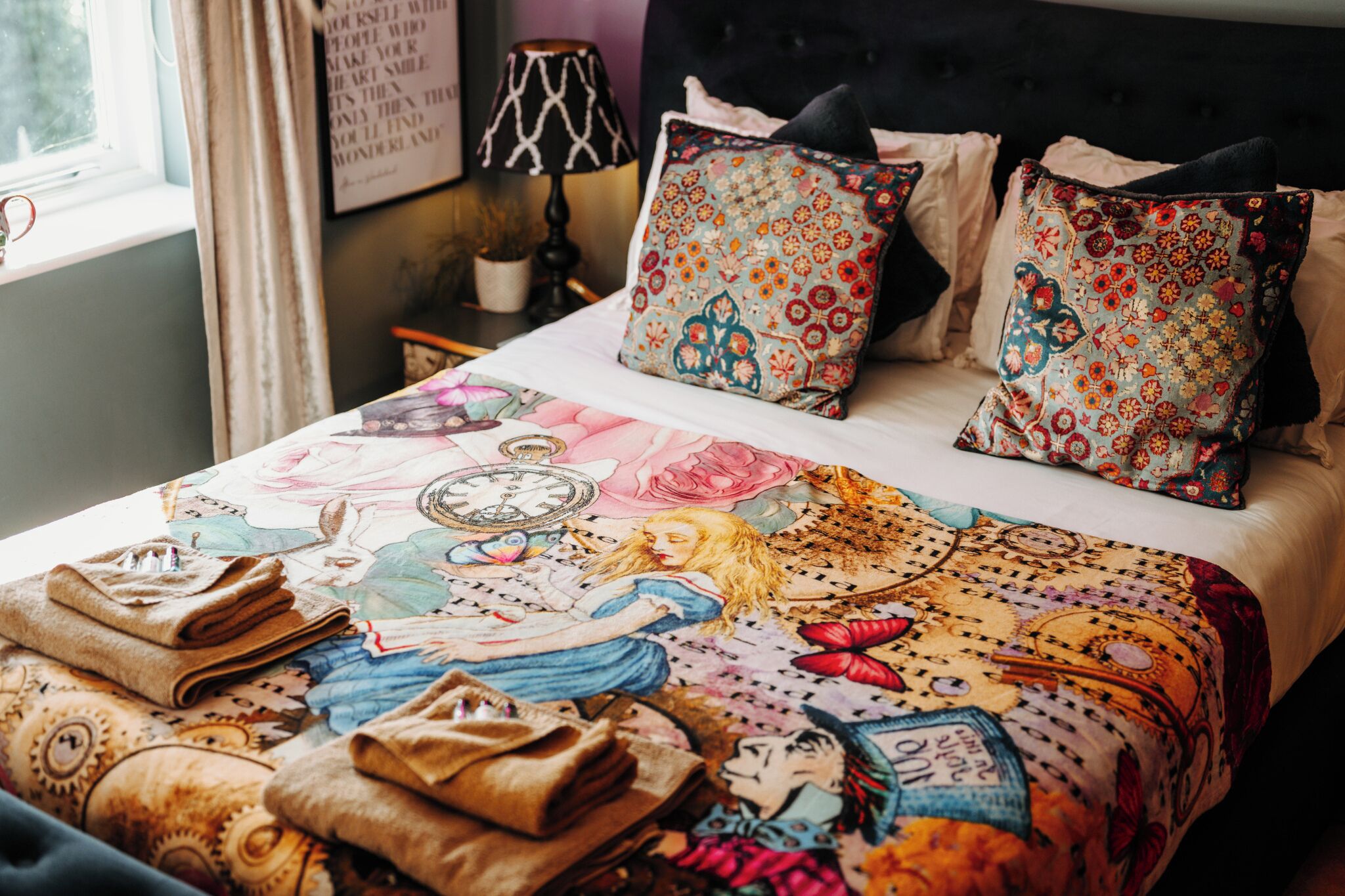 Un letto con una coperta illustrata e dai colori vivaci e cuscini a fantasia.