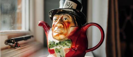 A ceramic teapot with a figure wearing a top hat on a windowsill.