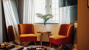 A hotel room with two red upholstered chairs, a small round table with a white vase, a radiator, and a standing heater. - Boutique Shrewsbury Rooms (Shrewsbury)