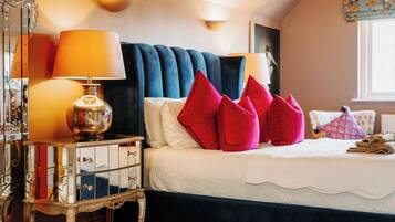 A bed with a white comforter, red pillows, and a blue headboard.