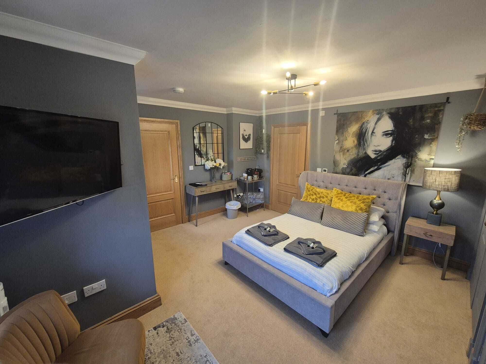 Un dormitorio con cama, televisión, escritorio y silla.