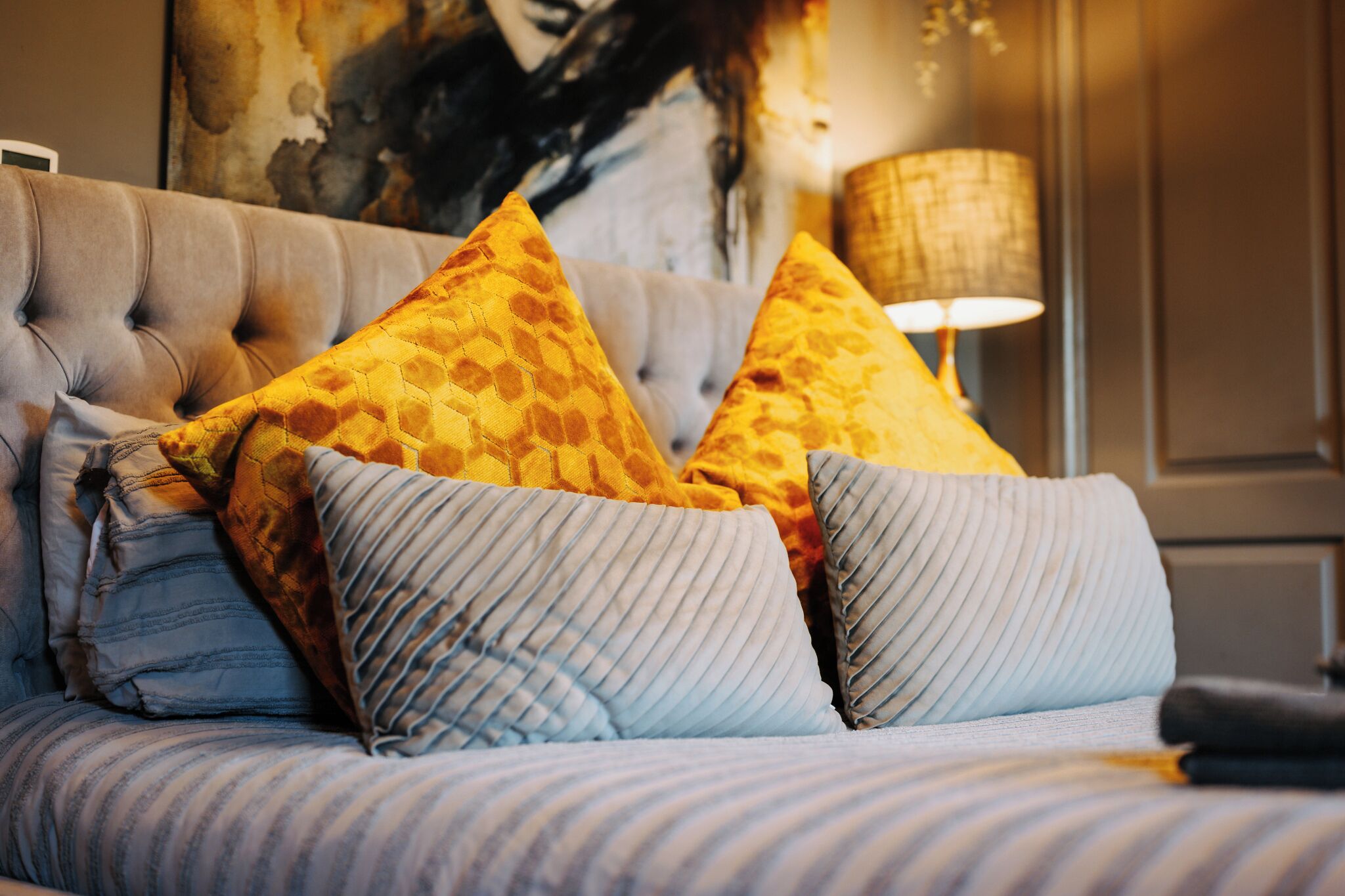 A bed with striped bedding and two pillows, one with a geometric pattern and the other ribbed.